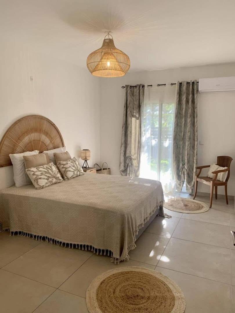 Chambre principale avec tête de lit en rotin et accès jardin